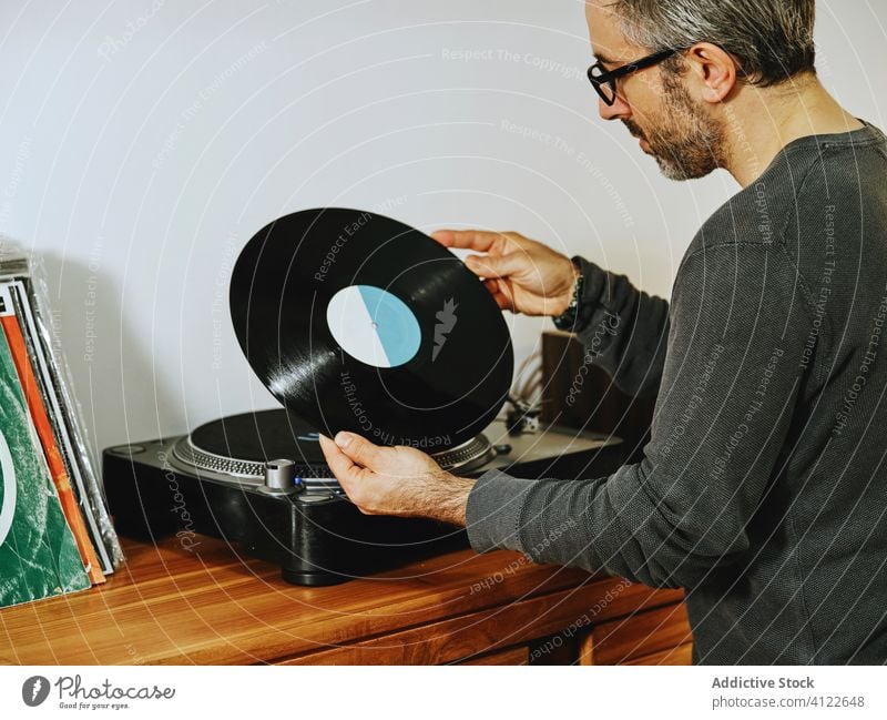 Gut aussehender Mann hört Musik auf einem Schallplattenspieler Vinyl Aufzeichnen Scheibe Plattenteller Spieler retro altehrwürdig Nostalgie zuhören Kälte