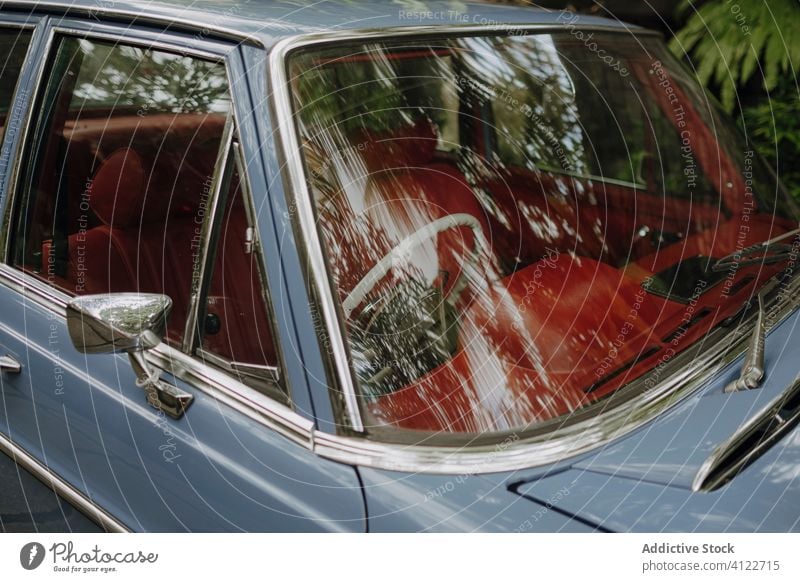 Glänzendes Retro-Auto im grünen Park PKW retro glänzend altehrwürdig geparkt tropisch Innenbereich Windschutzscheibe Antiquität Bali Indonesien Baum