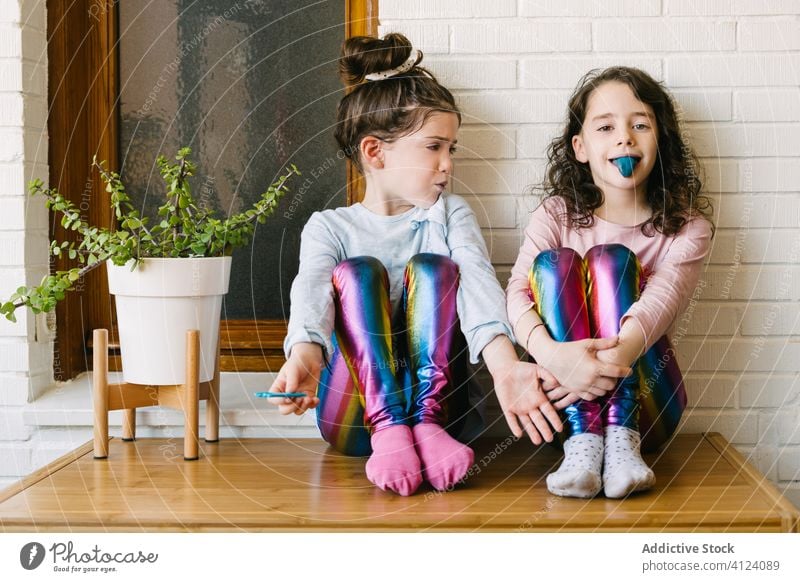 Fröhliche kleine Mädchen essen blaue Kaubonbons Kauen Bonbon Leckerbissen süß teilen heimwärts Spaß Glück Kinder geschmackvoll Lachen lecker Schwester Pyjama