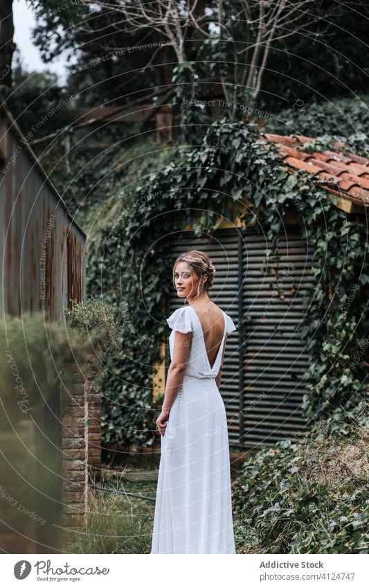 Braut zu Fuß in der Nähe des Zauns im Garten Frau Spaziergang Hochzeit elegant Sommer romantisch Veranstaltung Kleid weiß grün Metall Gelassenheit feiern Heirat