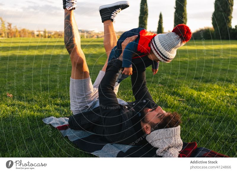 Junger Vater hat Spaß mit kleinem Sohn im Park Kind Zusammensein Wiese Glück Spaß haben Liebe heiter Lügen Gras Kleinkind positiv Herbst Kindheit Natur Freude