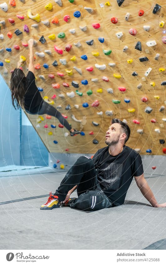 Unbekannter Mann schaut Kletterer in der Turnhalle an Aufsteiger Training Fitnessstudio Ausbilderin Aufstieg Trainer Felsbrocken Sport Hobby beobachten Club