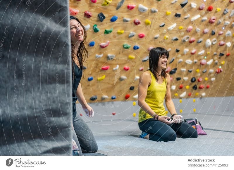 Zufriedene Kletterin beim Ausruhen nach dem Training im Fitnessstudio Frau Aufsteiger Sport Lächeln Lachen genießen sitzen Wand Griff sich[Akk] entspannen Gerät