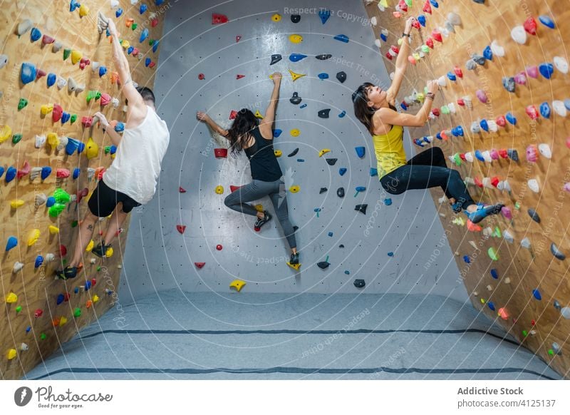 Bergsteiger in Sportkleidung an der Wand in der Turnhalle Aufstieg Training Felsbrocken Hobby Gerät Fitnessstudio Aktivität Frauen Mann Menschengruppe bereit