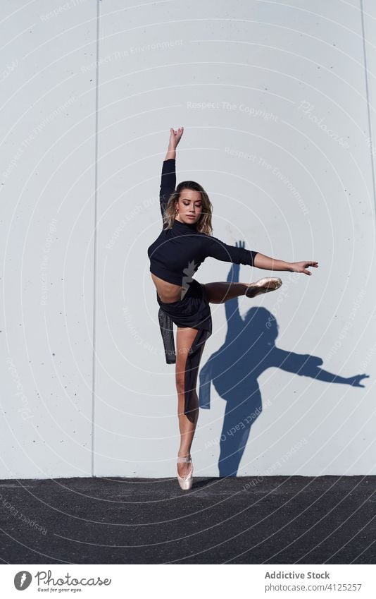 Anmutige Ballerina tanzt vor einer weißen Wand Frau Tänzer zierlich ausführen weiße Wand Straße auf Zehenspitzen Tanzen Flüssigkeit Balletttänzer Schatten