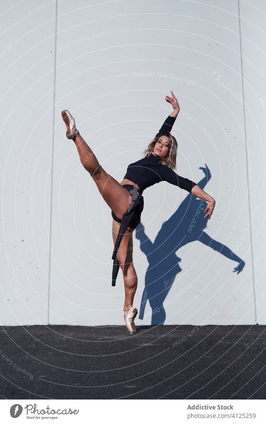 Anmutige Ballerina tanzt vor einer weißen Wand Frau Tänzer zierlich ausführen stehen weiße Wand Straße auf Zehenspitzen Tanzen Flüssigkeit Balletttänzer