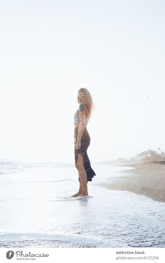 Schlankes junges Weibchen am feuchten Sandstrand stehend Frau Meereslandschaft Harmonie Einsamkeit Frieden winken Hipster nass MEER allein Küste Windstille