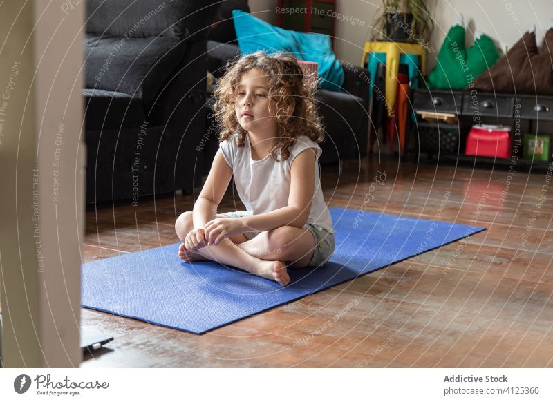 Kleines Mädchen lernt zu Hause online Yoga Kind Laptop üben heimwärts zuschauen Video Tutorial lernen Pose Gerät Apparatur Internet benutzend Unterlage wenig