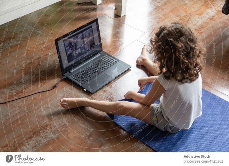 Kleines Mädchen lernt zu Hause online Yoga Kind Laptop üben heimwärts zuschauen Video Tutorial lernen Pose Gerät Apparatur Internet benutzend Unterlage wenig