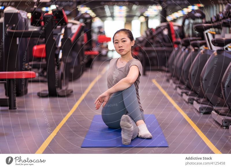 Starke junge ethnische Sportlerin beim Dehnen auf einer Matte im Fitnessstudio Unterlage Dehnung Training Aufwärmen passen Club schlank schlanke Wellness Übung