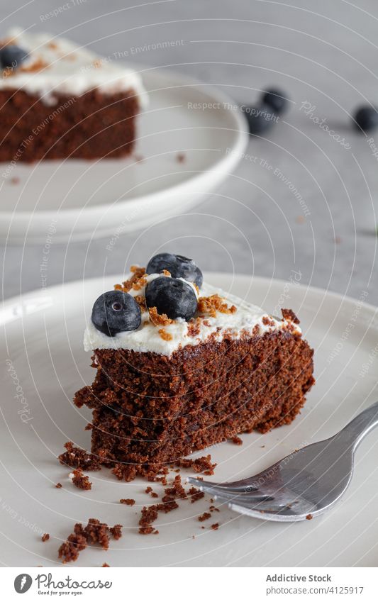 Ein Stück frischer Schokoladenkuchen mit Blaubeeren und Sahne dekoriert auf dem Küchentisch Spielfigur Kuchen gepeitscht Scheibe Schwamm Biskuit weiß