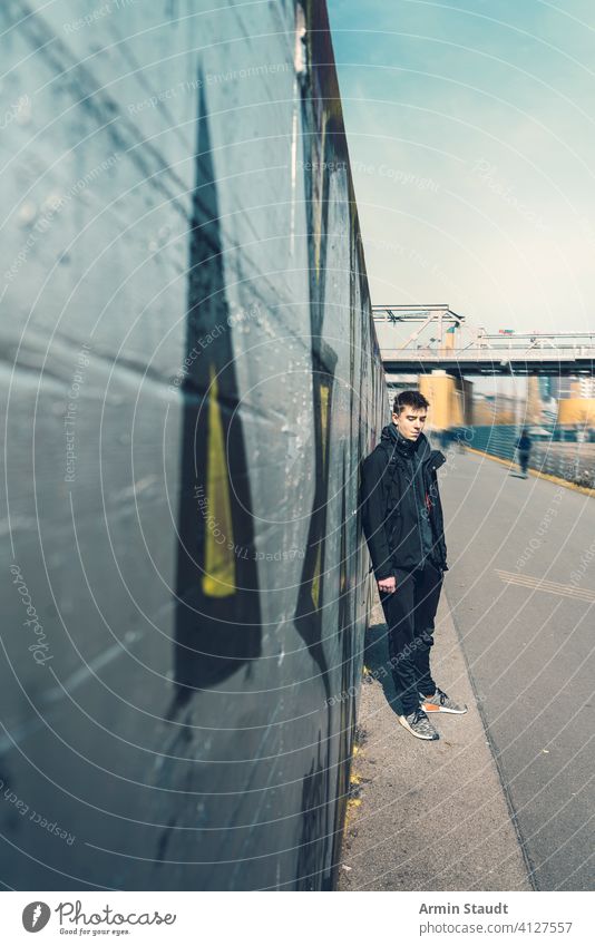 Porträt eines traurigen jungen Mannes, der an einer Wand lehnt Lehnen Silber im Freien beunruhigt müde Stehen Perspektive abnehmend Brücke Eisenbahn Jogger