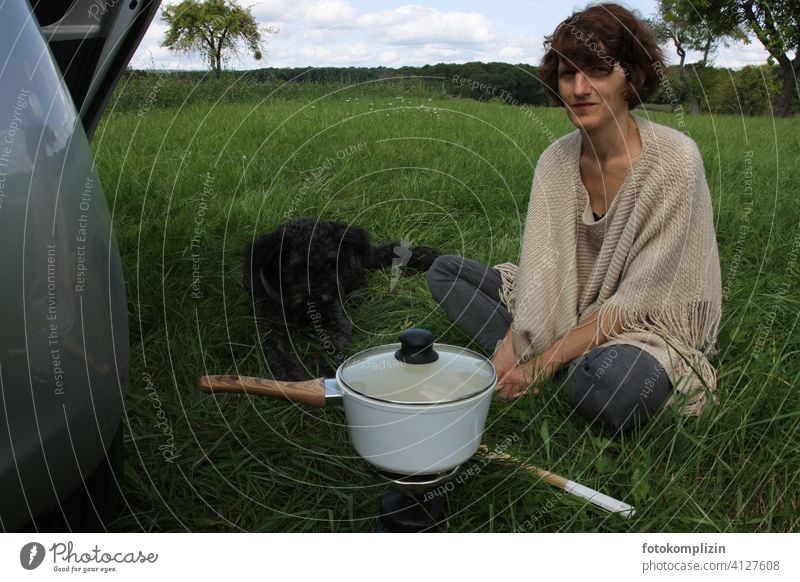 Frau mit Hund und Kochtopf auf einer Wiese Gaskocher Picknick Ausflug Campingkocher Topf Ferien & Urlaub & Reisen Urlaubsgefühl Mittagessen Freizeit Mahlzeit