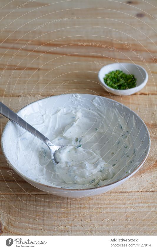 Schüssel mit Sauerrahmsauce mit Kräutern auf dem Tisch Saucen Schalen & Schüsseln geschmackvoll Zwiebel grün mischen lecker selbstgemacht Lebensmittel