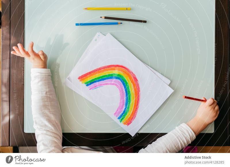 Mädchen zeichnet Bild auf Papier am Tisch zu Hause Zeichnung Regenbogen Bleistift kreativ Optimist positiv farbenfroh hell Inspiration Kind Kunst Farbe zeichnen