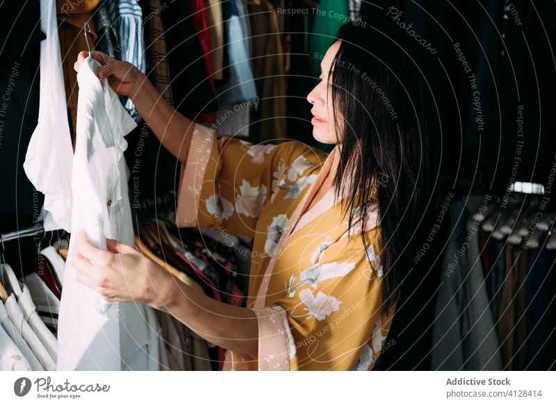 Junge attraktive Frau mit Kleidung in der Garderobe Kleiderschrank Kleidungsstück pflücken heimwärts Robe Bekleidung Stoff wählen Outfit Mode Stil brünett Wahl