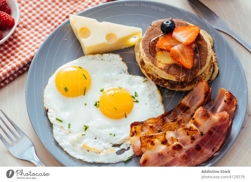 Leckere Spiegeleier mit Speck und Käse zum Frühstück Teller Ei Muffins erdbeeren schwarze Beeren Liebling Lebensmittel dienen Mahlzeit gebraten Pfannkuchen