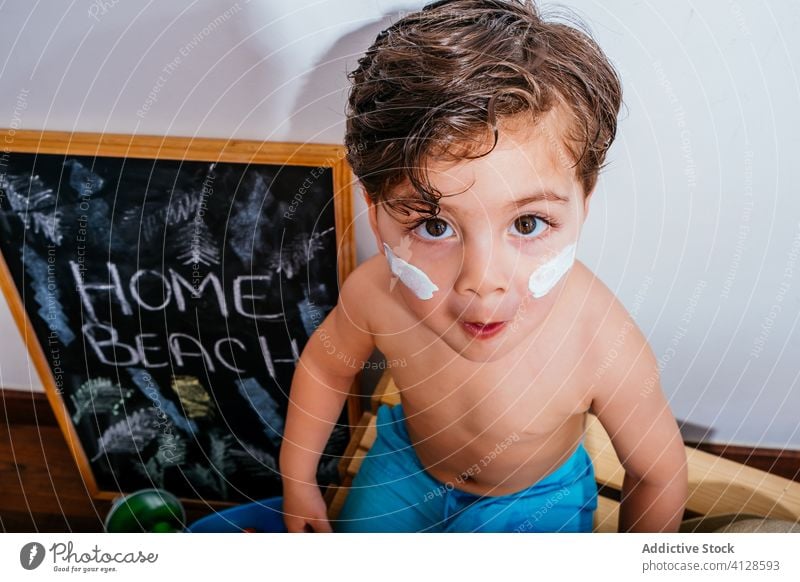 Fröhliches Kind, das auf einer Holzkiste sitzt und den Strand zu Hause genießt Junge heimwärts Spaß Glück Quarantäne Selbstisolierung träumen Vorfreude warten