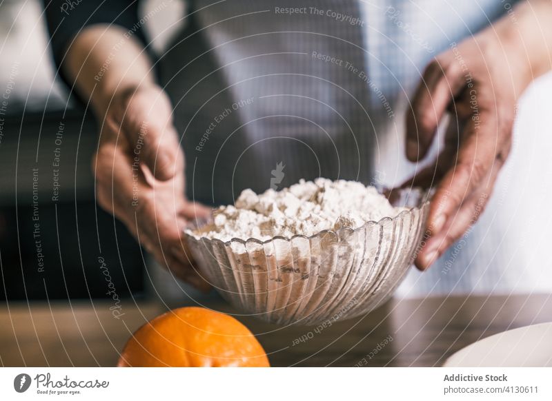 Crop Senior Koch hält Mehl Schüssel in der Küche Schalen & Schüsseln Teigwaren Glas Prozess machen Bestandteil Konditor vorbereiten Schürze Gebäck älter