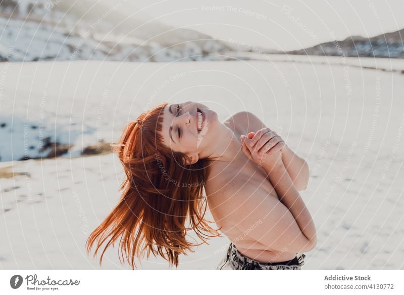 Junge Frau mit roten Haaren steht in einem verschneiten Feld rote Haare oben ohne Winter fliegendes Haar Natur Glück Schnee sich[Akk] entspannen Wind