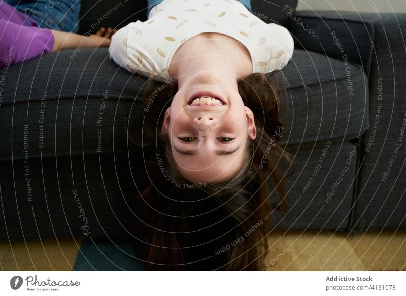 Glückliche Geschwister, die gemeinsam auf dem Sofa zu Hause Spaß haben Mädchen Kinder heimwärts auf den Kopf gestellt Menschengruppe Lachen Stock heiter