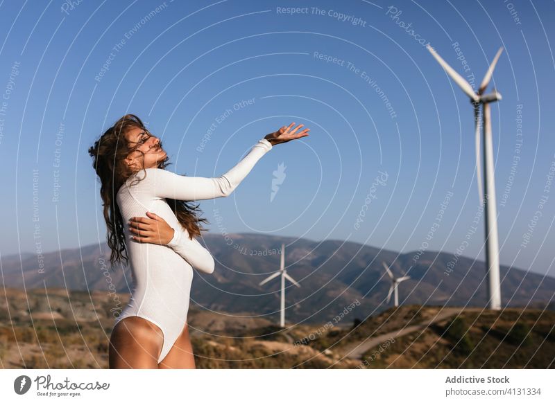 Zarte Frau tanzt allein in der Nähe des Windparks auf sonnigem Feld Tanzen Landschaft sinnlich Natur Ökologie schlank Stil alternativ Windmühle Energie