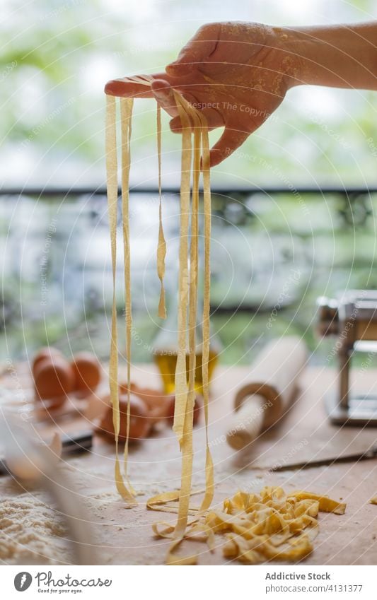 Nicht erkennbare Frau mit geschnittener roher Pasta Spätzle selbstgemacht Teigwaren Gurt dünn Streifen Gebäck Koch Tisch Mehl Küchengeräte rollen Eierschale