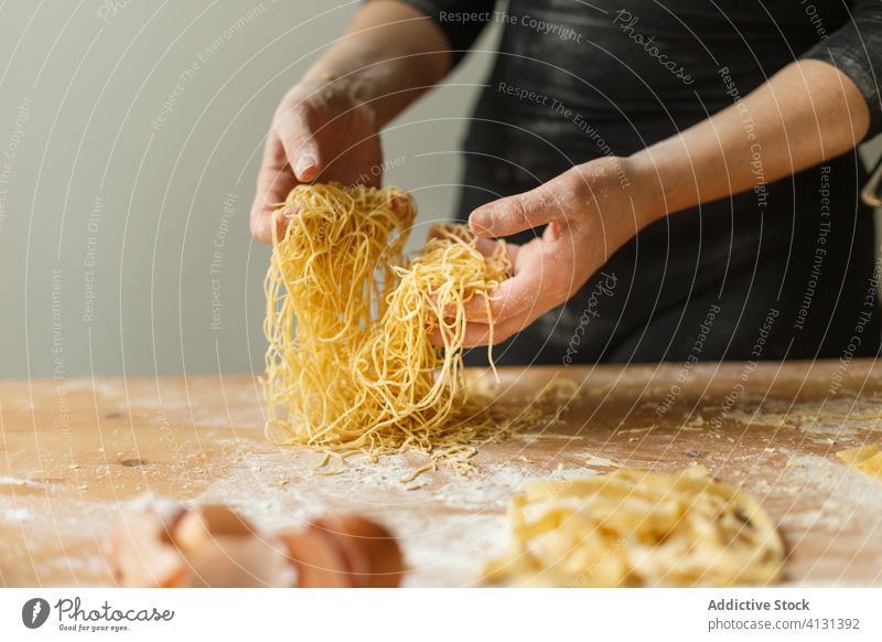 Nicht erkennbare Frau mit geschnittener roher Pasta Spätzle selbstgemacht Teigwaren Gurt dünn Streifen Gebäck Koch Tisch Mehl Küchengeräte rollen Eierschale