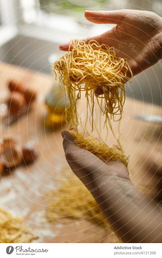 Nicht erkennbare Frau mit geschnittener roher Pasta Spätzle selbstgemacht Teigwaren Gurt dünn Streifen Gebäck Koch Tisch Mehl Küchengeräte rollen Eierschale