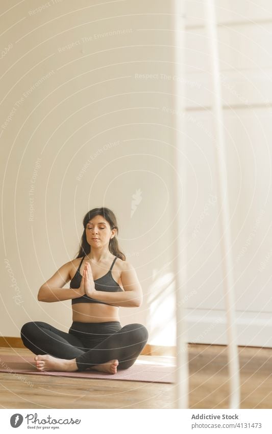 Ruhige Frau meditiert in Lotus-Pose meditieren Yoga Namaste padmasana Achtsamkeit ruhig Fokus heimwärts Konzentration Übung Unterlage Training Gelassenheit