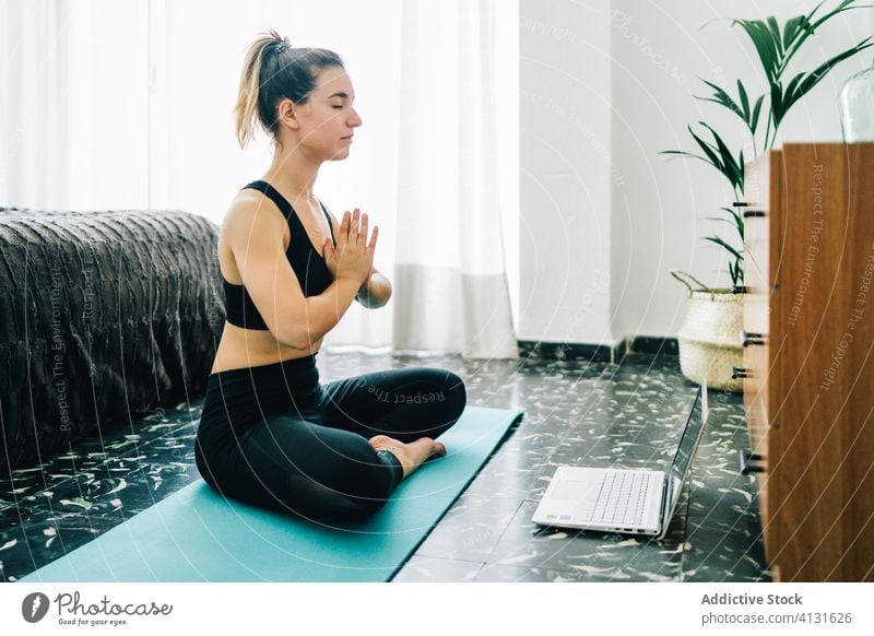 Junge Frau, die zu Hause online Yoga praktiziert meditieren Laptop heimwärts Lotus-Pose Namaste Windstille jung gestikulieren Tutorial üben Wellness Asana Gerät