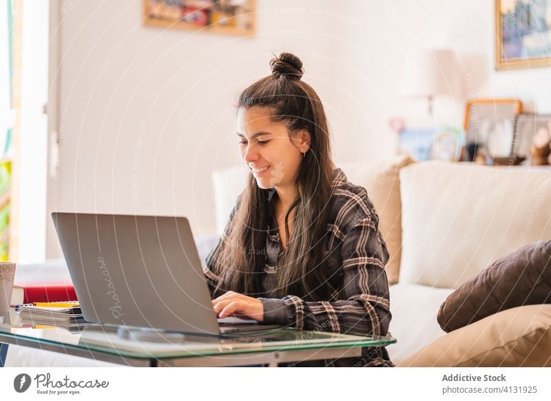 Junge Frau arbeitet mit Laptop im Wohnzimmer heimwärts benutzend Arbeit freiberuflich Sofa jung lässig abgelegen Gerät Apparatur Browsen Internet Lifestyle