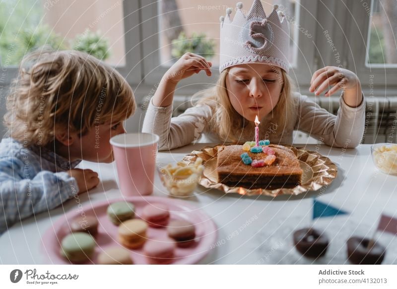 Kleines Mädchen bläst Kerze auf Geburtstagskuchen während einer Party zu Hause Kuchen Wunsch Schlag Glück feiern heimwärts Freude charmant Krone Filz dekorativ