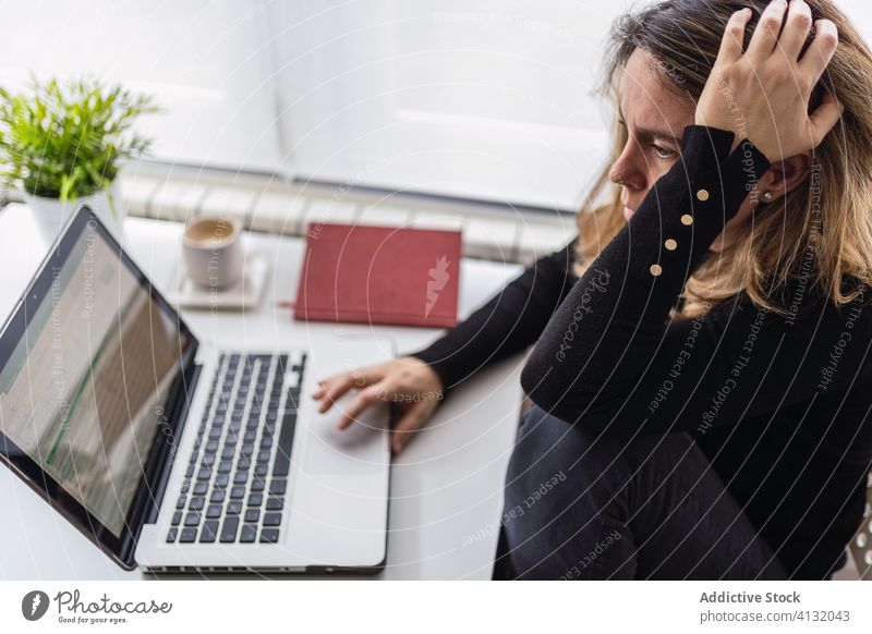 Entfernte Mitarbeiter, die zu Hause mit einem Laptop arbeiten Frau Arbeit heimwärts benutzend online abgelegen beschäftigt lässig ernst Tisch elektronisch