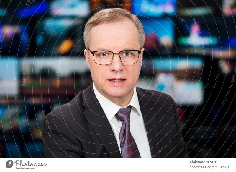 Ein Moderator, der live über aktuelle Nachrichten berichtet, sitzt im Fernsehstudio. Hintergrund von mehreren Bildschirmen von Broadcast-Kontrollraum. Journalismus Konzept