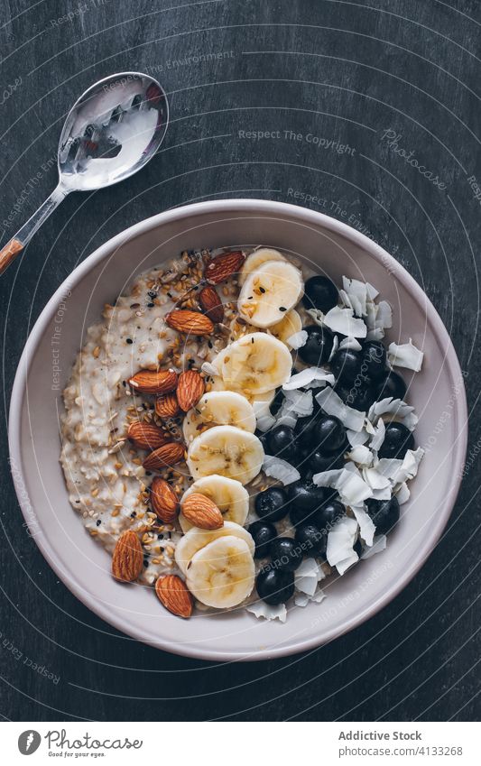 Schale mit Haferbrei Blaubeeren Mandeln Banane Kokosnuss Saatgut Löffel Korn Frucht Haferflocken Lebensmittel Frühstück Schalen & Schüsseln Gesundheit Müsli