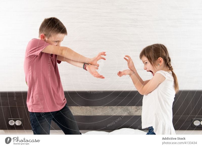 Fröhliche Geschwister spielen auf dem Bett spielerisch Geschwisterkind Spaß haben heimwärts Schlafzimmer Zusammensein Wochenende Schwester Bruder unterhalten