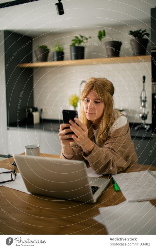 Freiberuflerin mit Smartphone in der Küche freiberuflich Pause Frau Buchhalter benutzend zuschauen abgelegen Arbeit heimwärts lustig Tisch Mobile Telefon