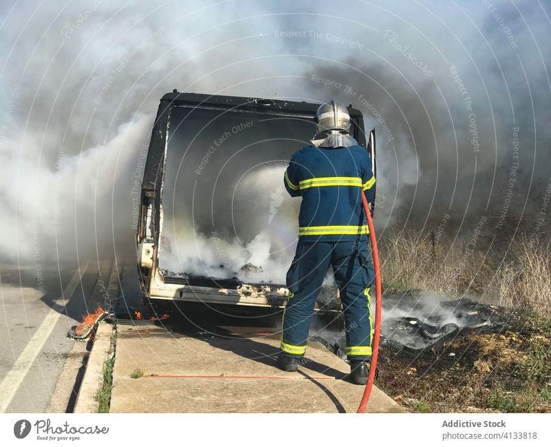 Feuerwehrmann löscht Feuer im Auto löschen PKW ausmachen Rauch Mut Wasser Schlauch Mitarbeiterin sonnig tagsüber Sommer Energie stark Notfall Dienst retten