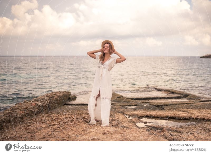 Zufriedene Frau in Kleid und Hut am Meer sorgenfrei reisen Meereslandschaft Seeküste Inhalt Lächeln Sommer Feiertag Meeresufer levanzo Insel Stein Reisender