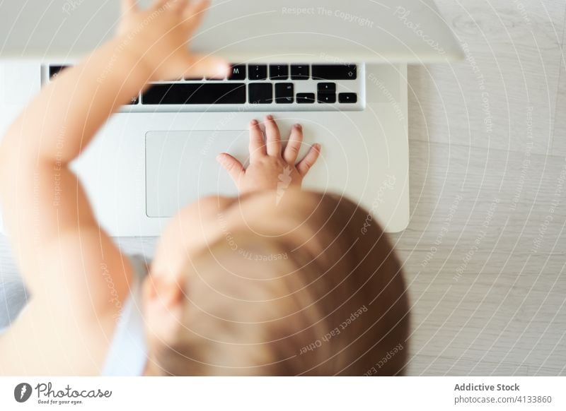 Anonymes Baby spielt mit Laptop zu Hause benutzend Draufsicht anonym heimwärts spielen Kleinkind Apparatur modern Kindheit Lifestyle wenig allein heiter Gerät