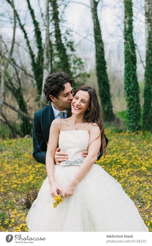 Fröhliches Brautpaar auf einer Blumenwiese Jungvermählter Umarmung Paar Hochzeit Wiese striegeln Hochzeitstag heiter Blütezeit Lächeln stilvoll Kleid Anzug