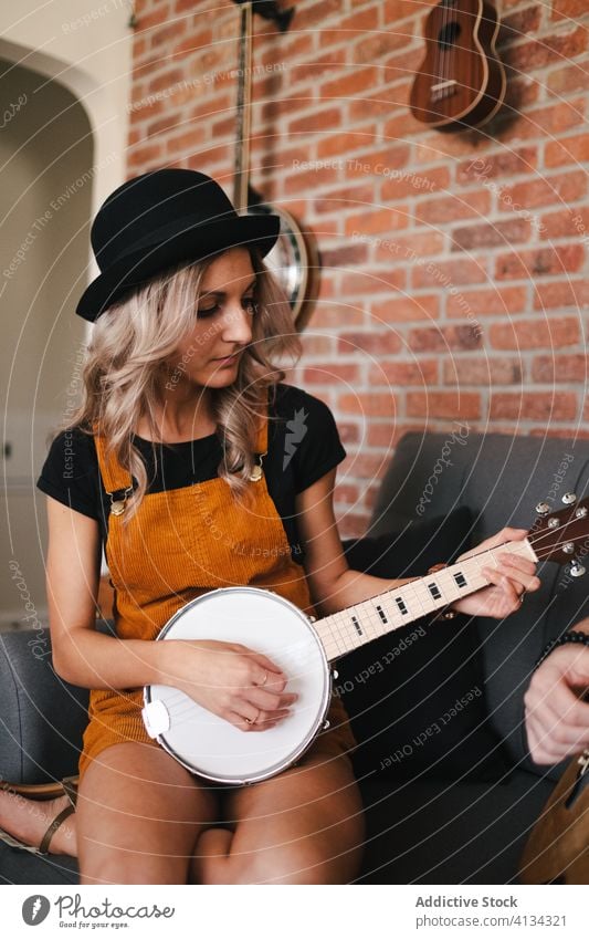 Junge Frau mit Banjo auf dem Sofa sitzend spielen banjo Musik Freizeit Beine gekreuzt Musical Instrument schlank flach lässig anhaben schlanke heimwärts