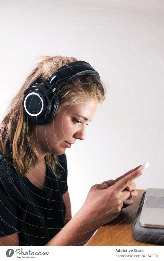 Fröhliche Frau mit Kopfhörern und Smartphone benutzend heiter jung zuhören Talkrunde Telefon Apparatur positiv Lächeln genießen Glück Musik heimwärts Gerät