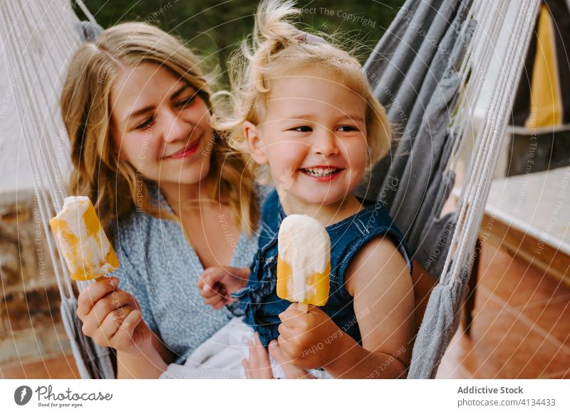 Glückliches kleines Mädchen und Frau mit hausgemachten Eis am Stiel Mutter Tochter Umarmung Stieleis selbstgemacht Kies genießen heiter Sommer Terrasse Lächeln