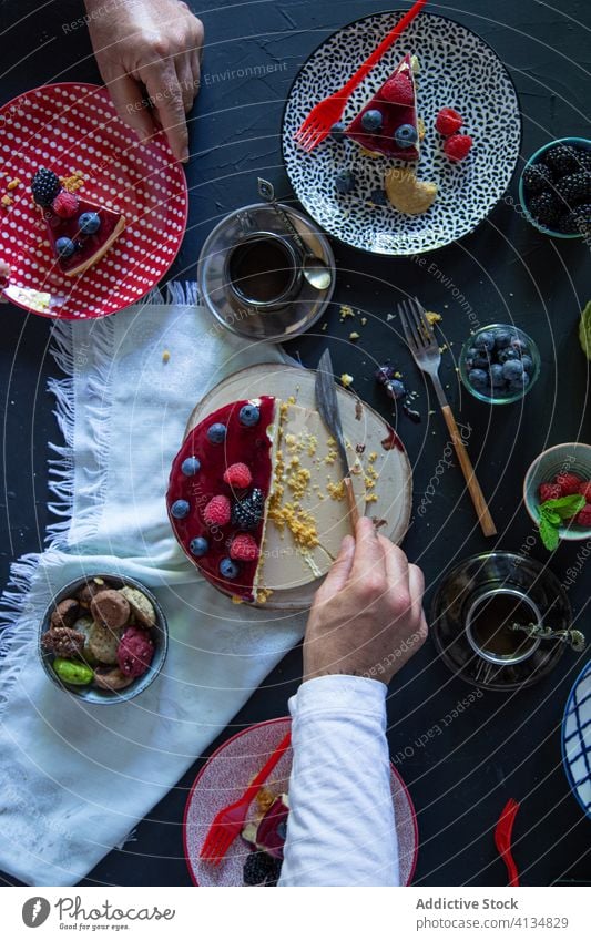 Person, die den Kuchen auf dem Tisch anschneidet geschnitten Beeren lecker Pasteten Frühstück dienen Kaffee Morgen Lebensmittel Dessert frisch süß geschmackvoll