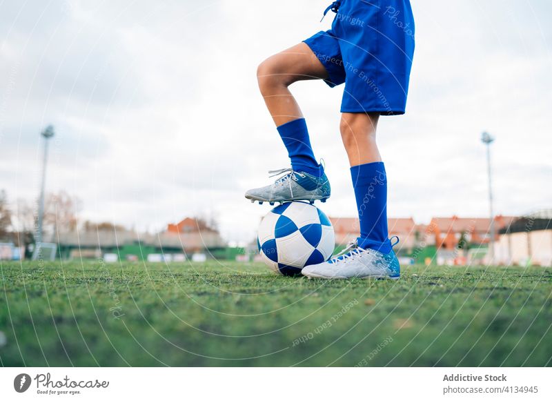 Crop weiblichen Spieler kicking Ball auf Fußballplatz in Sportverein Mädchen Kick Torwart Training Klampen Handschuh Feld spielen Uniform Kind Tierpfleger Arena