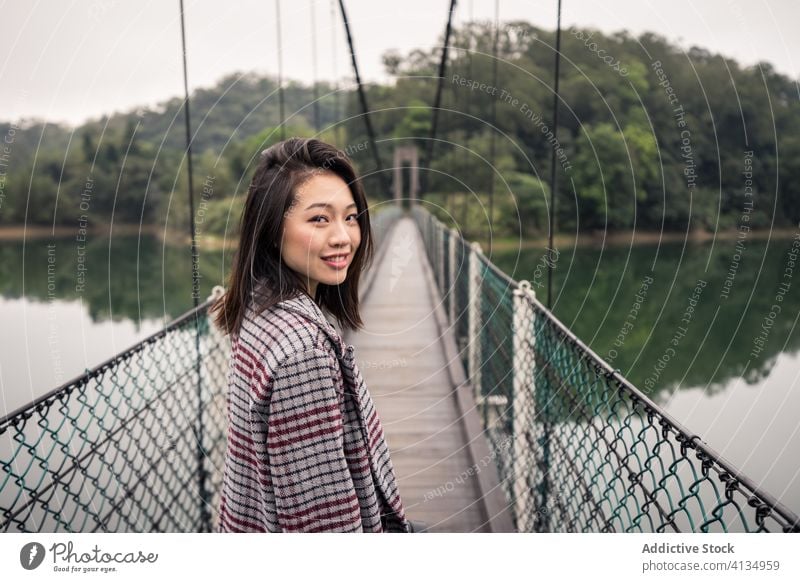 Ruhige asiatische Reisende auf Hängebrücke über Fluss stehend Tourist Suspension Brücke Wald Abenteuer Tourismus Urlaub malerisch friedlich Gelassenheit