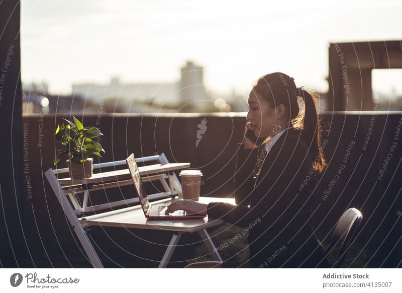 Geschäftige Frau mit Laptop arbeitet auf dem Dach Arbeit Smartphone benutzend reden Geschäftsfrau formal Dachterrasse Gerät Apparatur Business asiatisch jung