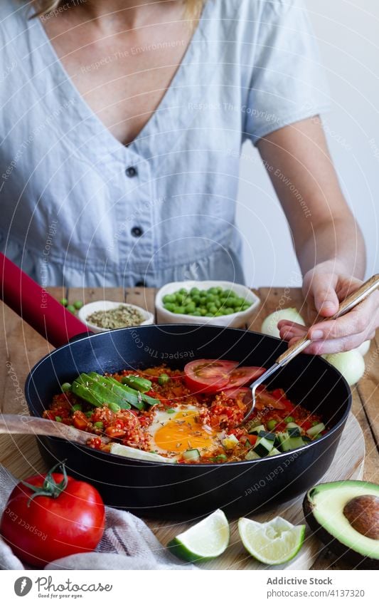 Crop-Frau isst leckere Shakshuka in der Küche shakshuka Ei Gemüse genießen Frühstück essen Bestandteil Speise Pfanne geschmackvoll Kalorie Tradition Quinoa